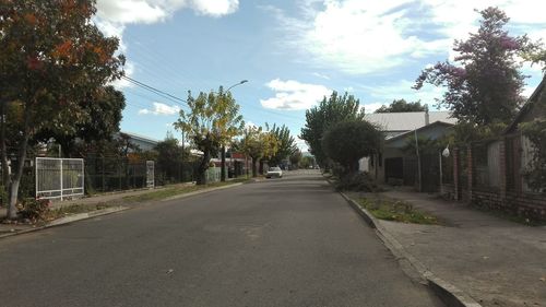 Road amidst trees in city against sky