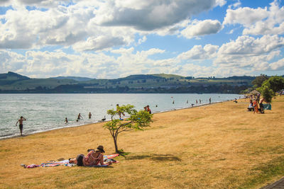 People on shore against sky