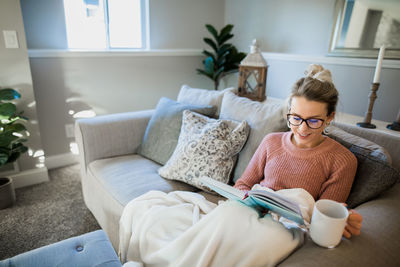 Midsection of woman sitting on sofa at home