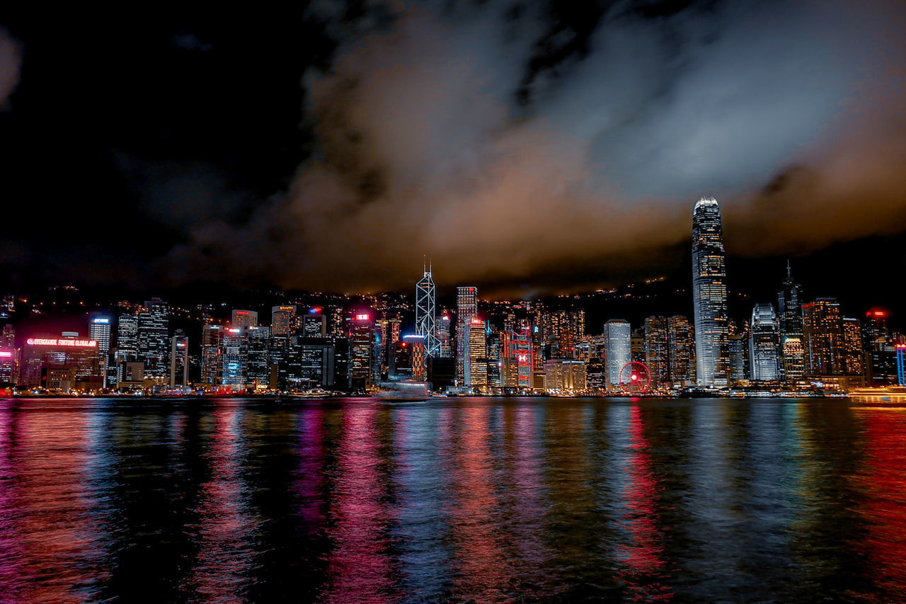 ILLUMINATED CITY BY SEA AGAINST SKY