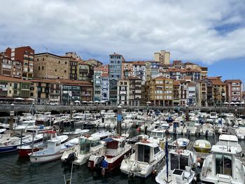 Sailboats moored at harbor against buildings in city