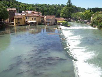 Scenic view of river by buildings against sky