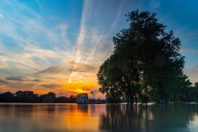 Silhouette trees by lake against sky during sunset