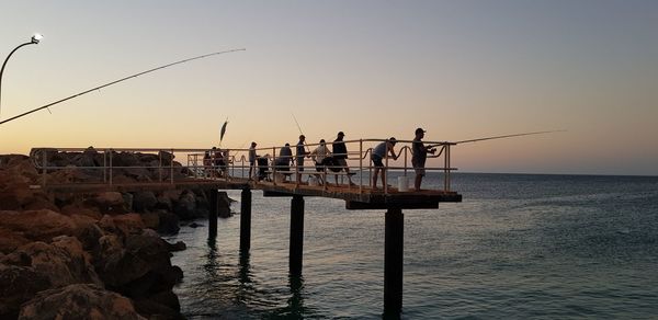 Silhouette pier on sea against clear sky during sunset