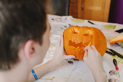 Close-up of baby boy carving pumpkin at table