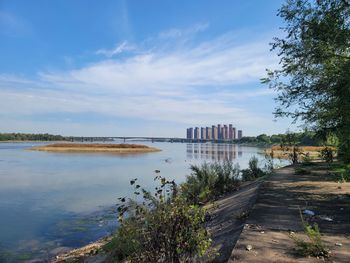Bridge over river by buildings against sky