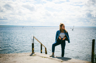 Woman standing at beach against sky