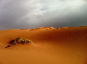 Scenic view of desert against cloudy sky