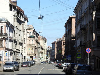 Cars on road amidst buildings against clear sky