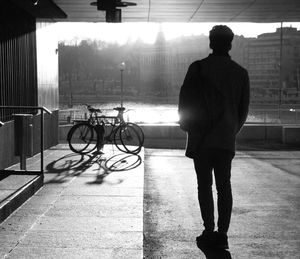 Rear view of silhouette man standing in parking lot during sunny day