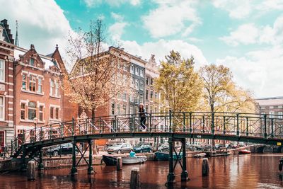 Woman standing on footbridge over canal in city