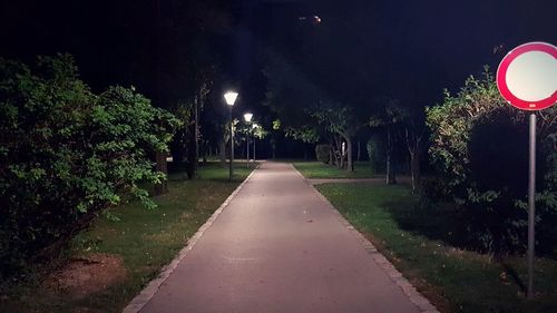 Street amidst trees in park at night