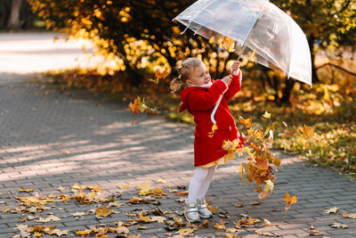 Cute girl holding umbrella while standing outdoors