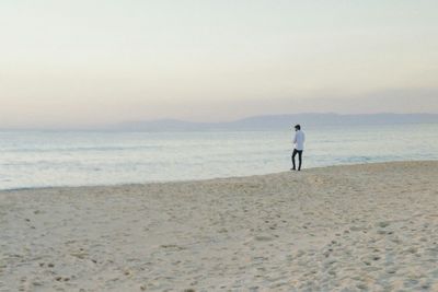 Rear view of man standing on beach against sky