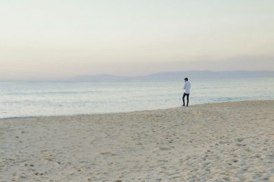 Rear view of man standing on beach against sky