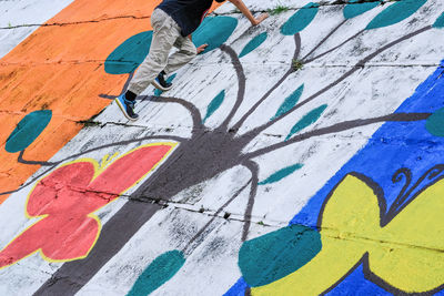 Low section of boy climbing on colorful graffiti wall