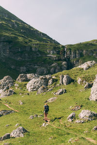 Rear view of female hiker on field against mountains