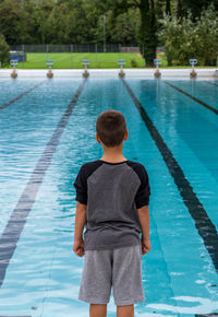 Rear view of boy standing at poolside
