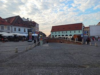 Road by buildings in city against sky