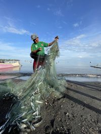 High angle view of man do net fishing on the beach