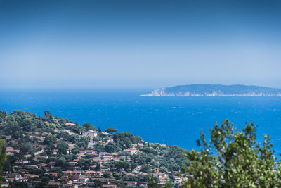 Scenic view of sea by city against clear blue sky