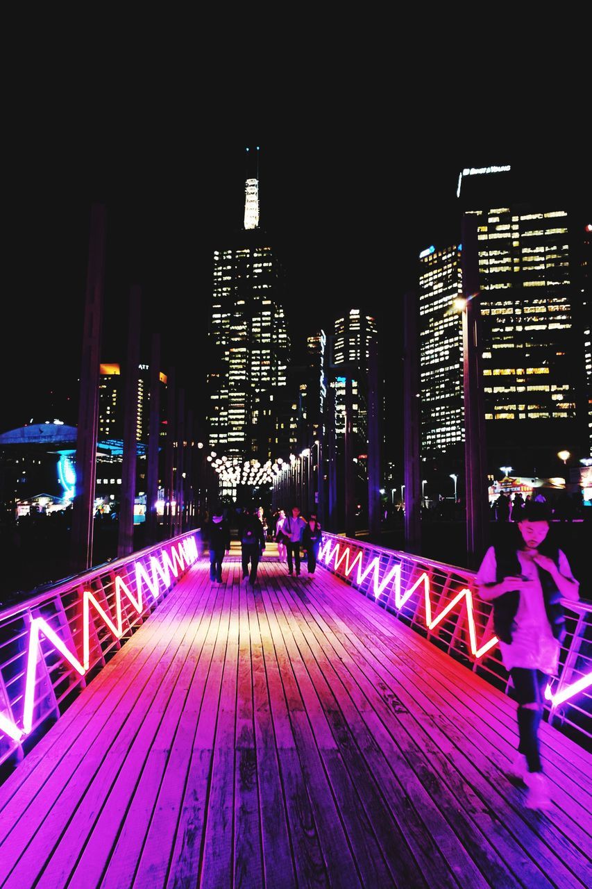 PEOPLE IN ILLUMINATED CITY AT NIGHT