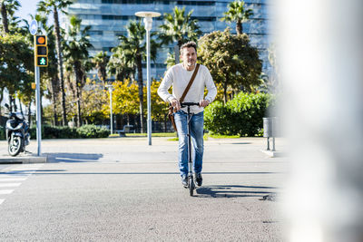 Mature man commuting in the city, using kick scooter on the pavemnet