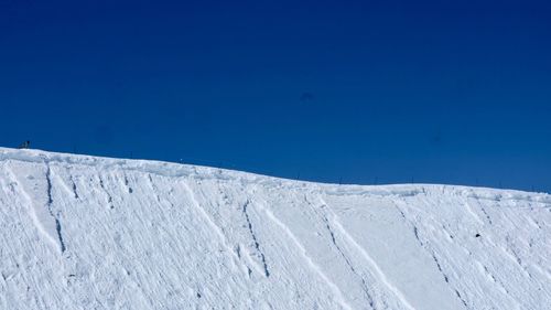 Low angle view of snow covered mountain against blue sky