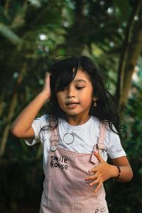Portrait of young woman standing against tree