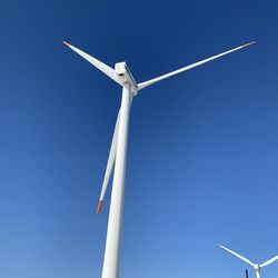 Low angle view of windmill against blue sky