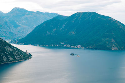 Scenic view of sea by mountains against sky