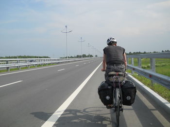 Rear view of man riding bicycle on highway