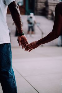 Cropped image of couple holding hands on street in city