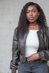 Portrait of young woman standing against wall