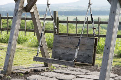 Empty wooden swing on field