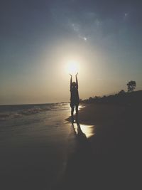 Silhouette man standing on beach against sky during sunset