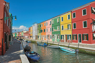 Colorful buildings and boats in front of a canal at burano, a little town full of canals in italy.