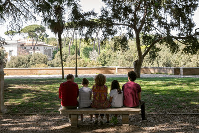 Rear view of people sitting on bench in park