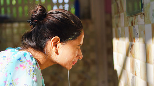 A beautiful woman is washing facial mask in bathroom after applying face mask.