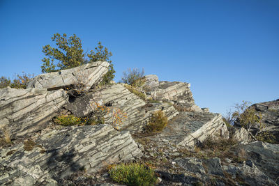 Low angle view of rock formation against clear blue sky