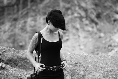 Woman with camera holding her belt while standing on field