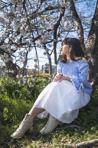 Woman sitting on grass against trees