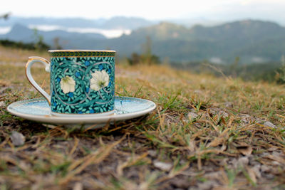 Close-up of coffee cup on field