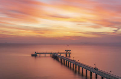 Pier over sea against sky during sunset