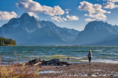 Woman standing on mountain by sea against sky