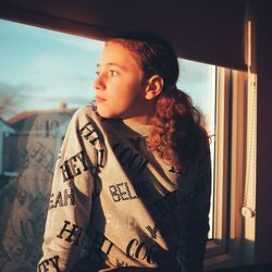 Portrait of teenage girl looking through window