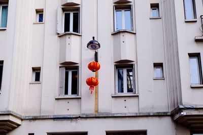 Low angle view of chinese lanterns hanging from street light against apartment building