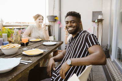 Portrait of smiling friends sitting on table