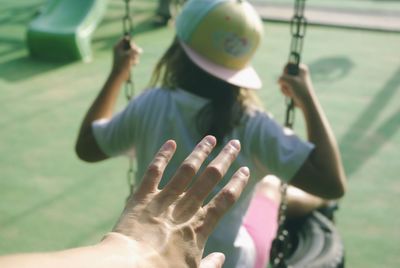 Cropped hand by girl swinging at park