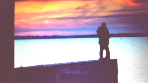 Rear view of silhouette woman standing against sky during sunset